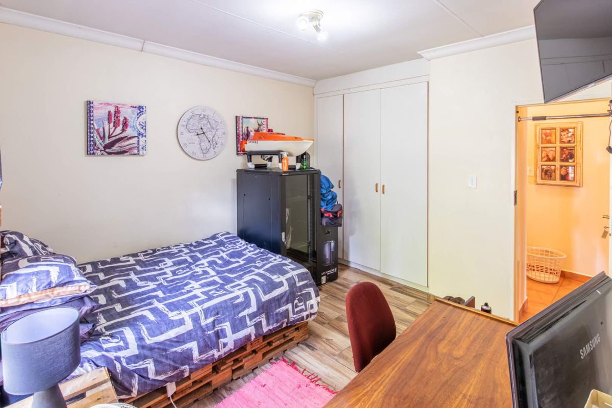A functional bedroom featuring built-in cupboards, laminate flooring, and coved ceiling details, providing a practical living space.