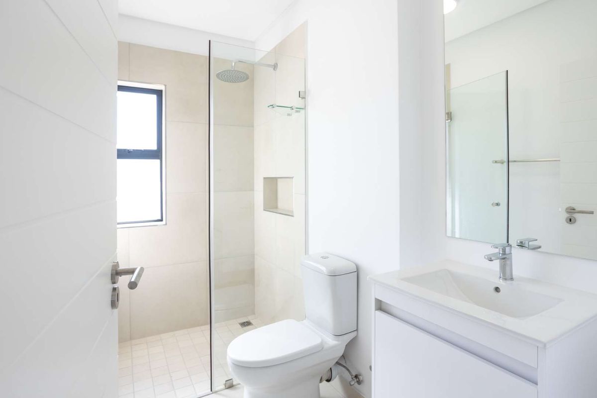 A modern, well-maintained bathroom featuring a glass-enclosed walk-in shower, a wall-mounted vanity with a basin, and a contemporary toilet.