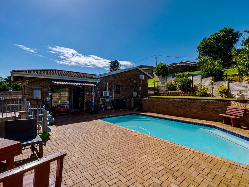 Outdoor pool area featuring brick paving, a retaining wall, and a brick house facade with a retractable awning.