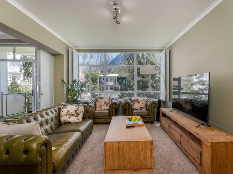 A comfortable living room featuring large windows with plantation shutters, offering natural light and scenic mountain views.