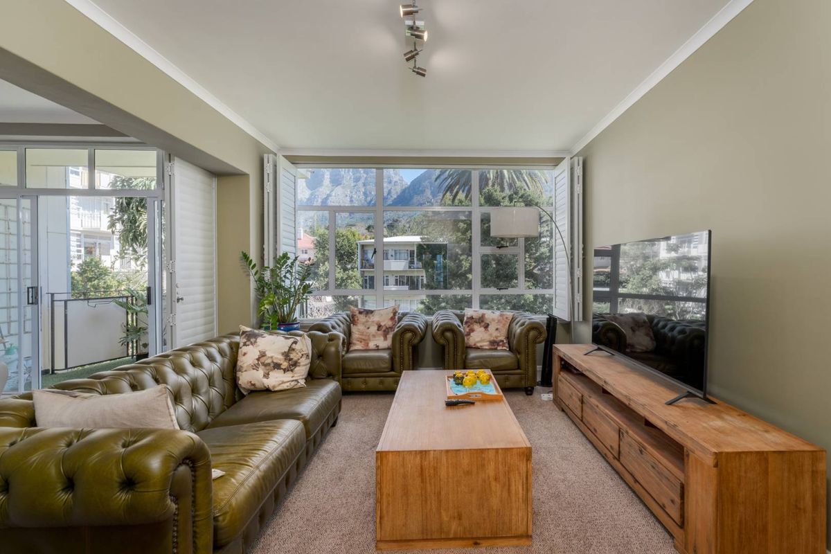 A comfortable living room featuring large windows with plantation shutters, offering natural light and scenic mountain views.