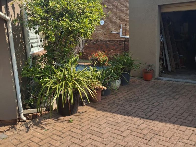 A paved rear courtyard area featuring a garage entrance and brick boundary walling.