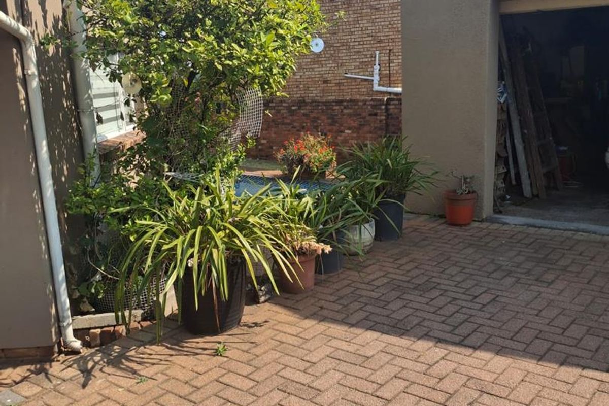 A paved rear courtyard area featuring a garage entrance and brick boundary walling.