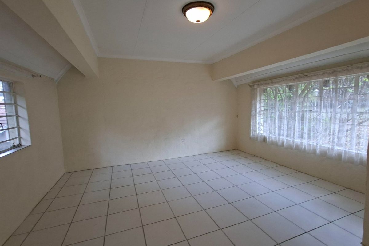 An empty bedroom featuring tiled flooring, neutral walls, and windows fitted with security bars, offering a blank canvas for personalization.