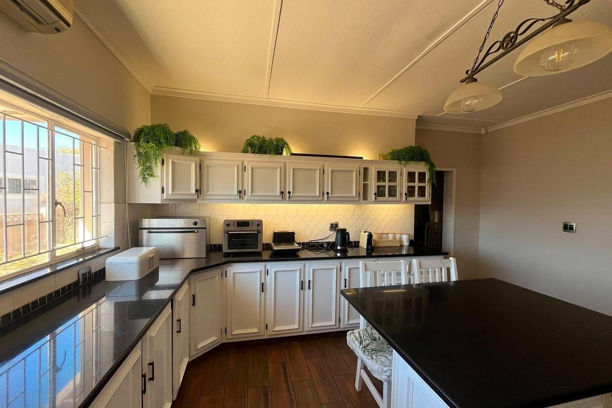 A well-maintained kitchen featuring white cabinetry, dark granite countertops, a central island, and integrated under-cabinet lighting.