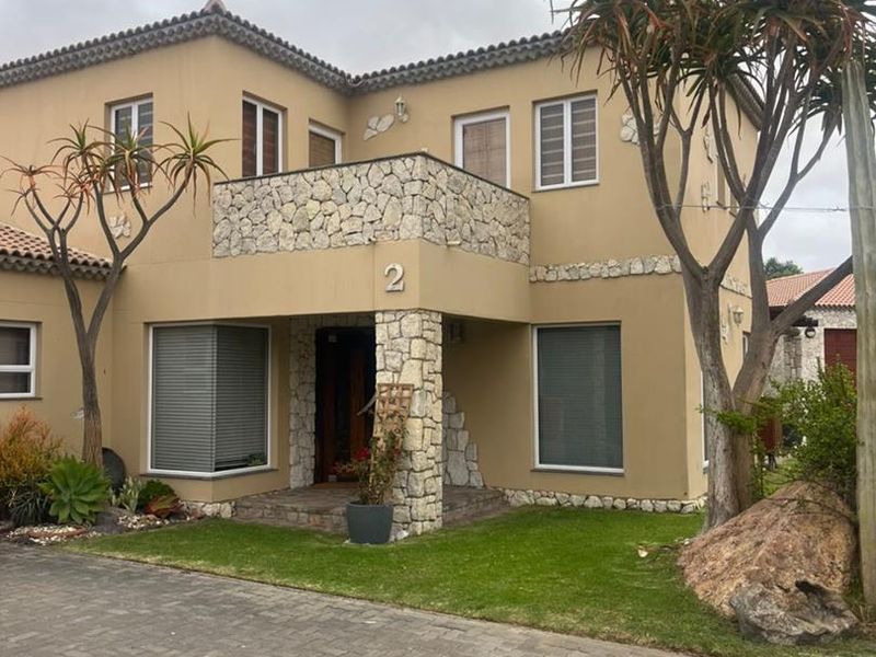 Front elevation of a two-story residential house featuring stone cladding accents, a tiled roof, and a paved driveway entrance.