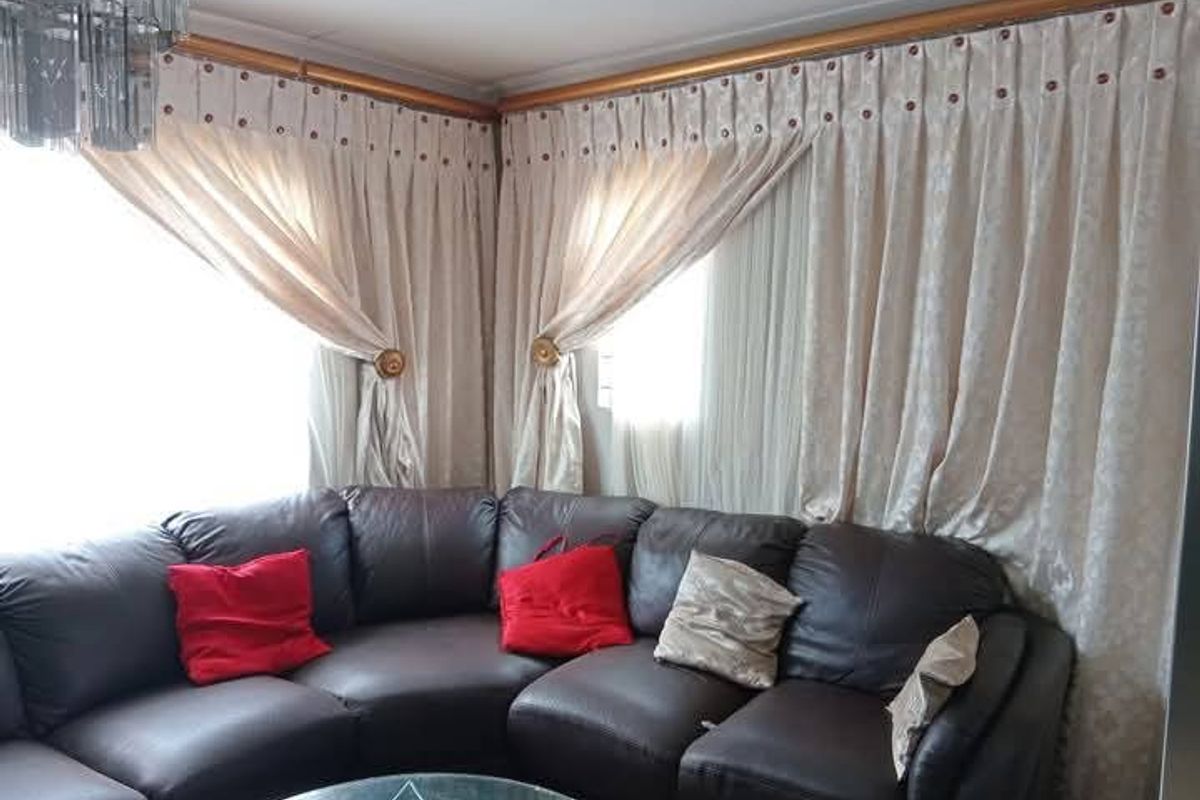 A cozy living room corner featuring floor-to-ceiling curtains and a modern crystal chandelier, creating a warm and inviting atmosphere.