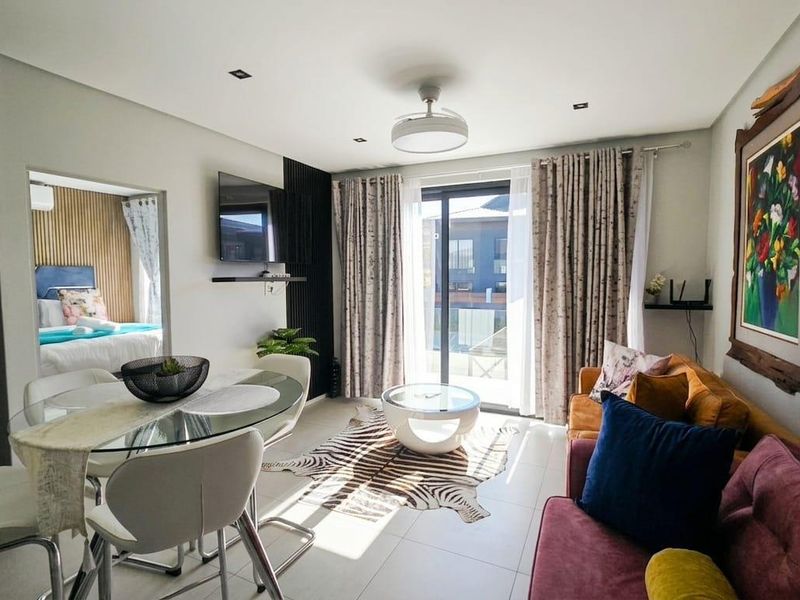 Modern open-plan living and dining area featuring tiled floors, recessed lighting, and a sliding glass door leading to an outdoor space.