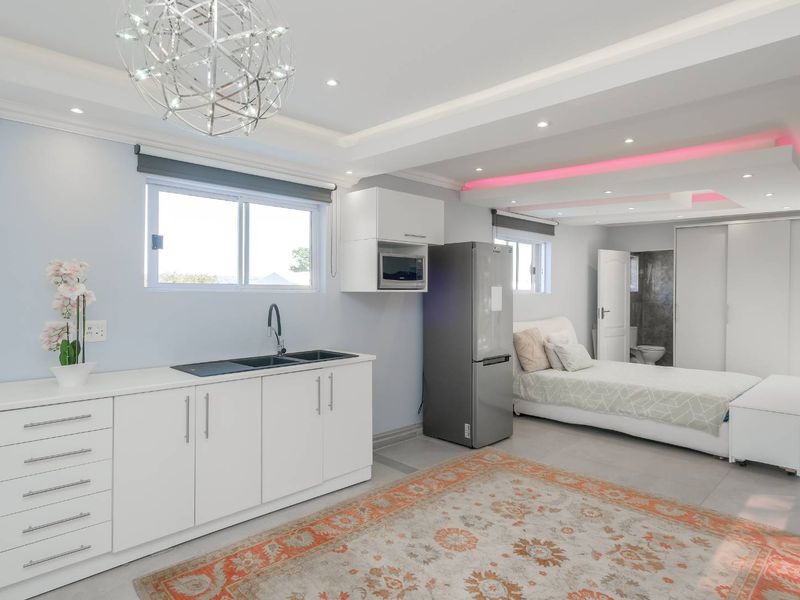 Modern open-plan studio apartment featuring a kitchenette with built-in cabinetry, recessed lighting, and an integrated bathroom area.