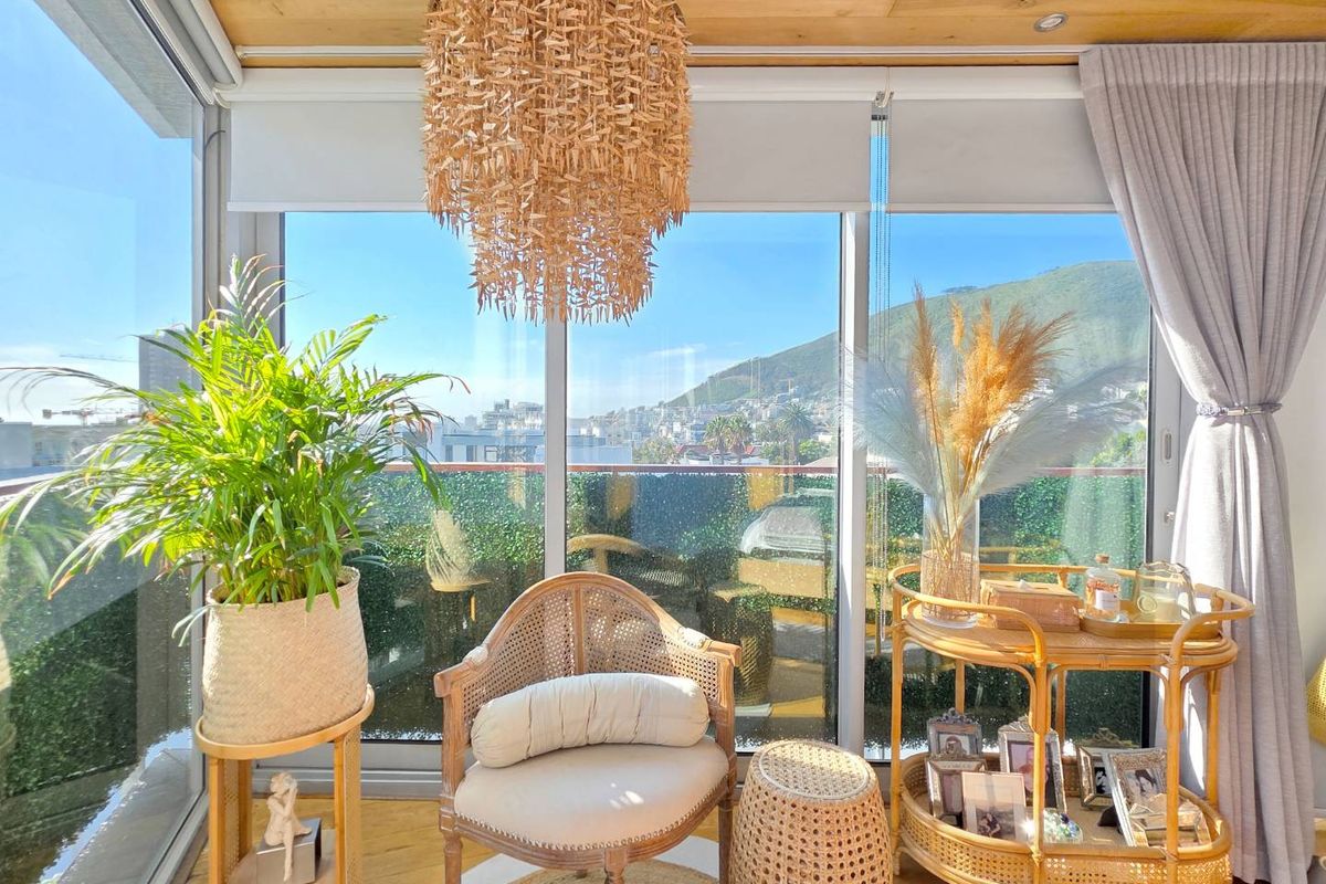 A bright living area featuring floor-to-ceiling glass windows, timber-look ceiling paneling, and expansive views of the surrounding landscape.