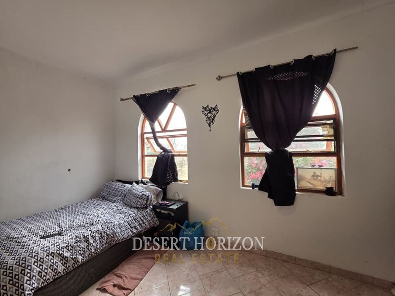 A bedroom featuring arched windows and tiled flooring, offering a functional space with potential for cosmetic updates to enhance its appeal.