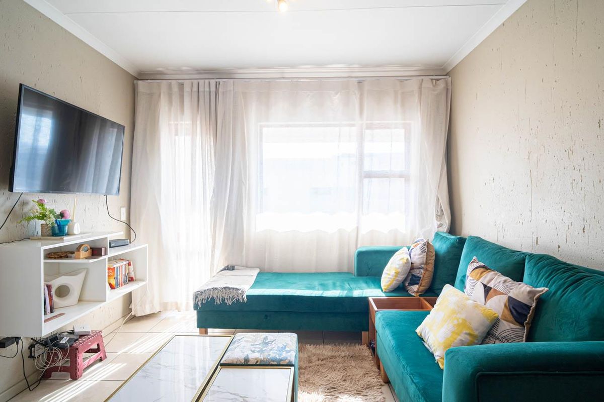 A comfortable living room featuring tiled flooring and large windows that allow for ample natural light.
