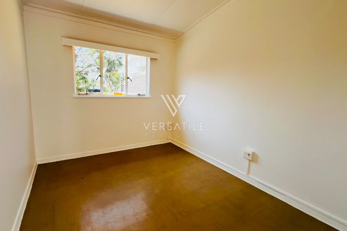 A vacant bedroom featuring neutral walls, a window, and dark flooring, providing a blank canvas for personalization.