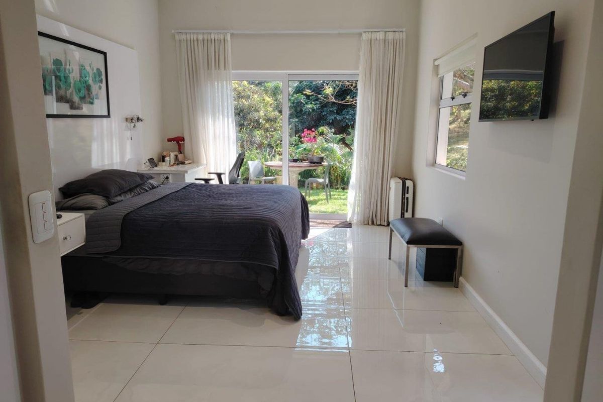 Spacious bedroom featuring polished tile flooring, large sliding glass doors providing garden access, and neutral wall finishes.
