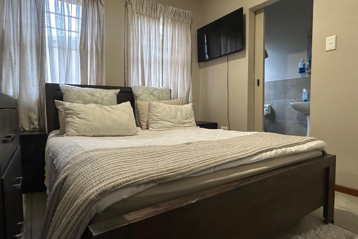 A bedroom featuring neutral walls, tiled flooring, and an en-suite bathroom accessible through a sliding door.