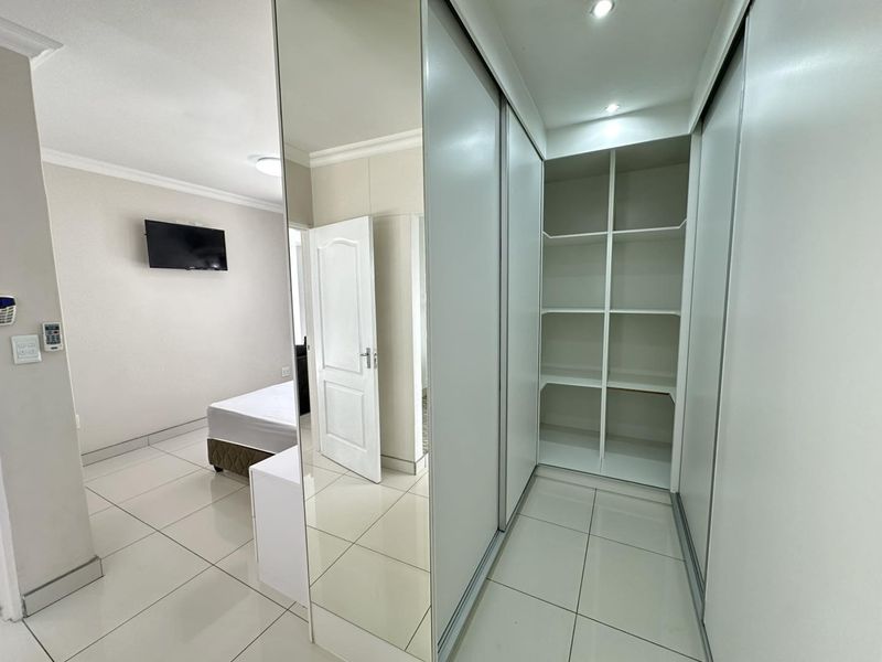 Bedroom featuring tiled flooring, recessed lighting, and extensive built-in cupboards with mirrored sliding doors for ample storage.