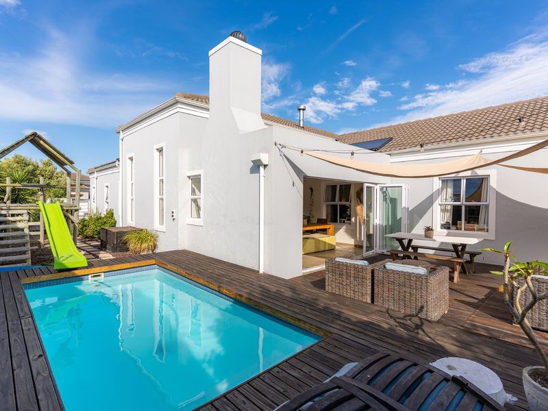Outdoor entertainment area featuring a swimming pool with timber decking, a shade sail, and direct access to the home via bi-fold doors.