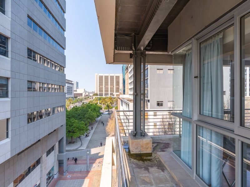 A balcony area featuring metal railings and an exposed structural column, offering an urban city view.