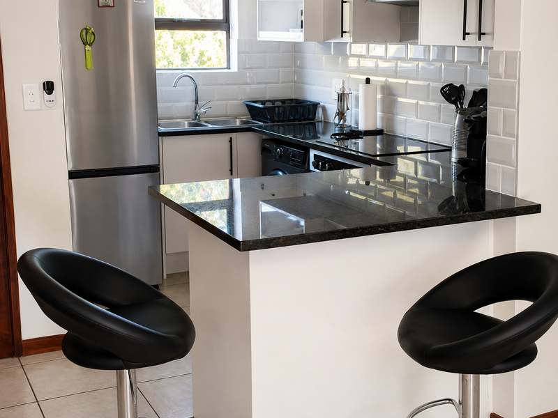 Modern kitchen featuring granite countertops, subway tile backsplash, and built-in cabinetry with a breakfast bar area.