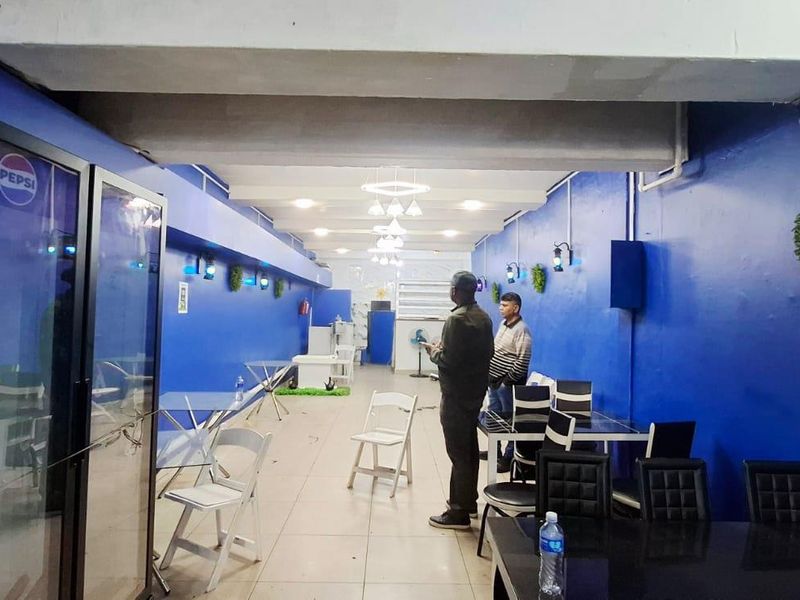 Open plan commercial space featuring tiled flooring and blue painted walls, suitable for a restaurant or cafe layout.