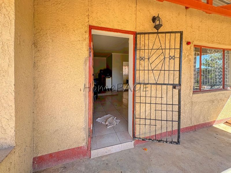 Entrance area featuring a security gate, tiled flooring, and exterior wall lighting, providing access to the main living space.