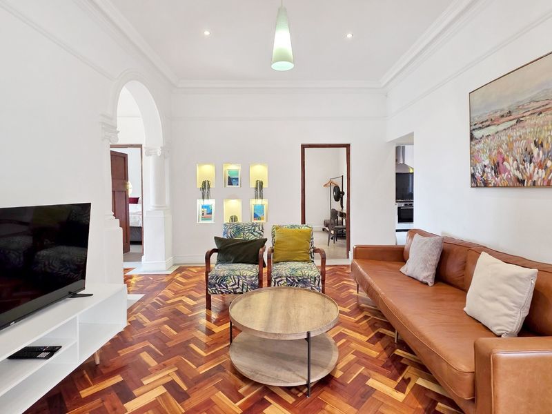 Spacious living room featuring classic herringbone parquet flooring, elegant arched architectural detailing, and built-in recessed wall niches with integrated lighting.
