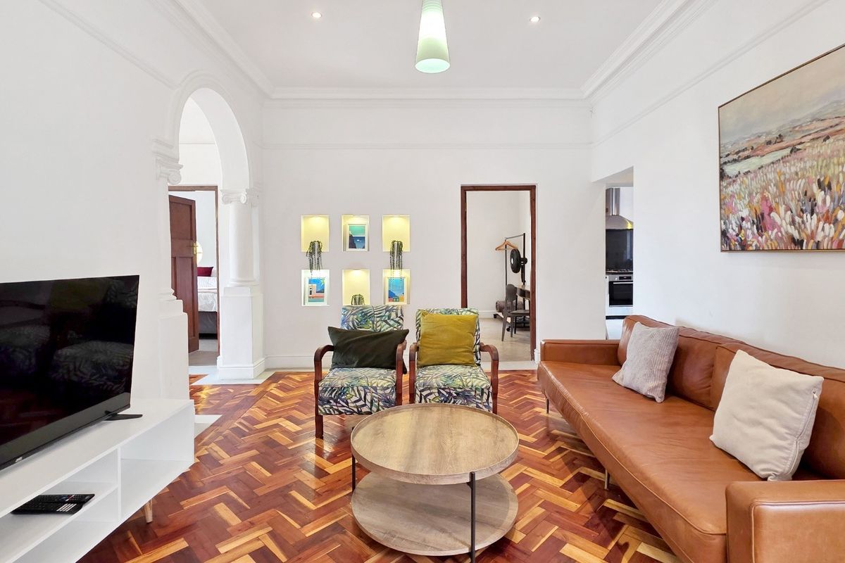 Spacious living room featuring classic herringbone parquet flooring, elegant arched architectural detailing, and built-in recessed wall niches with integrated lighting.