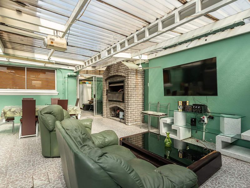Covered patio area featuring a built-in brick braai, tiled flooring, and a translucent roof, providing a functional space for outdoor entertaining.