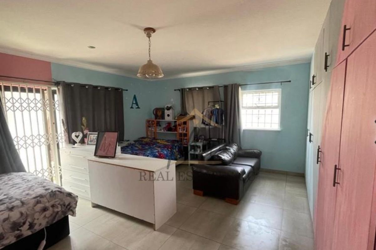 Spacious bedroom featuring built-in wardrobes, tiled flooring, and a security gate leading to an outdoor area.