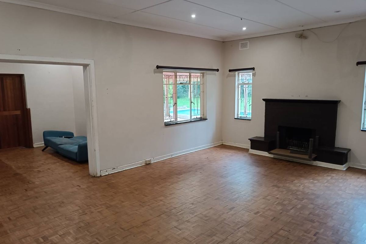 Spacious living room featuring original parquet flooring, a built-in fireplace, and recessed ceiling lighting, offering a blank canvas for renovation.