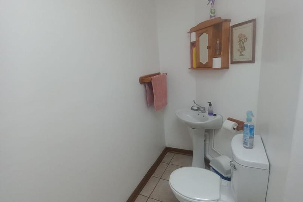 A compact office restroom featuring a pedestal sink, standard toilet, and tiled flooring.