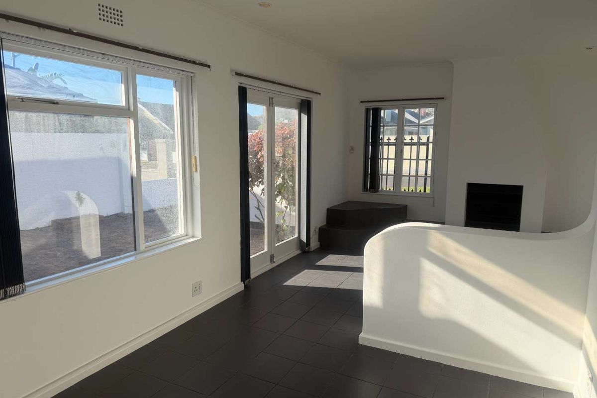 Bright living area featuring dark tiled flooring, a built-in fireplace, and large windows with direct access to the outdoor space.