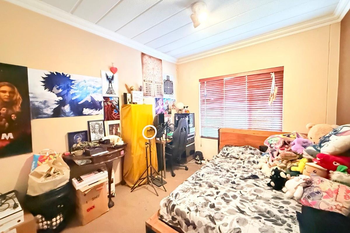 A bedroom featuring carpeted flooring, a window with fitted blinds, and a textured ceiling finish.