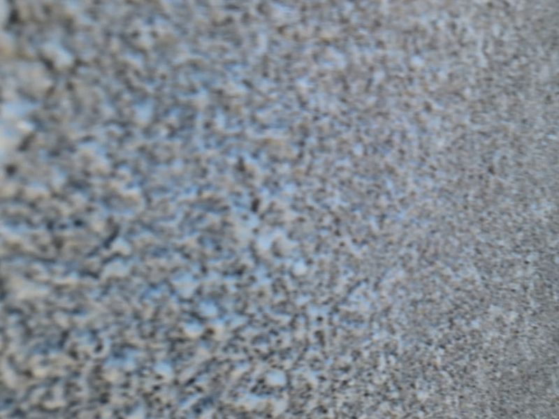 A close-up, out-of-focus image showing a textured concrete or stucco surface.