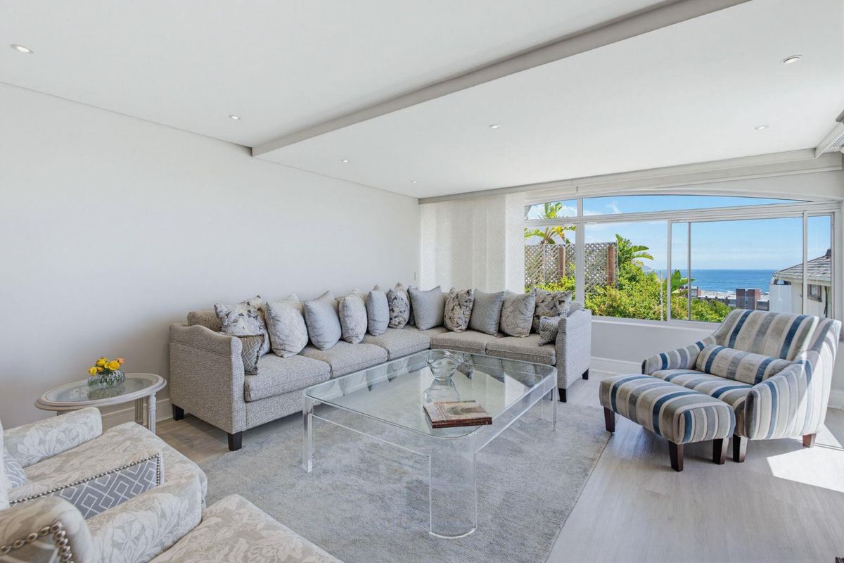 Bright and spacious living room featuring recessed ceiling lighting, light-toned laminate flooring, and a large window offering scenic coastal views.