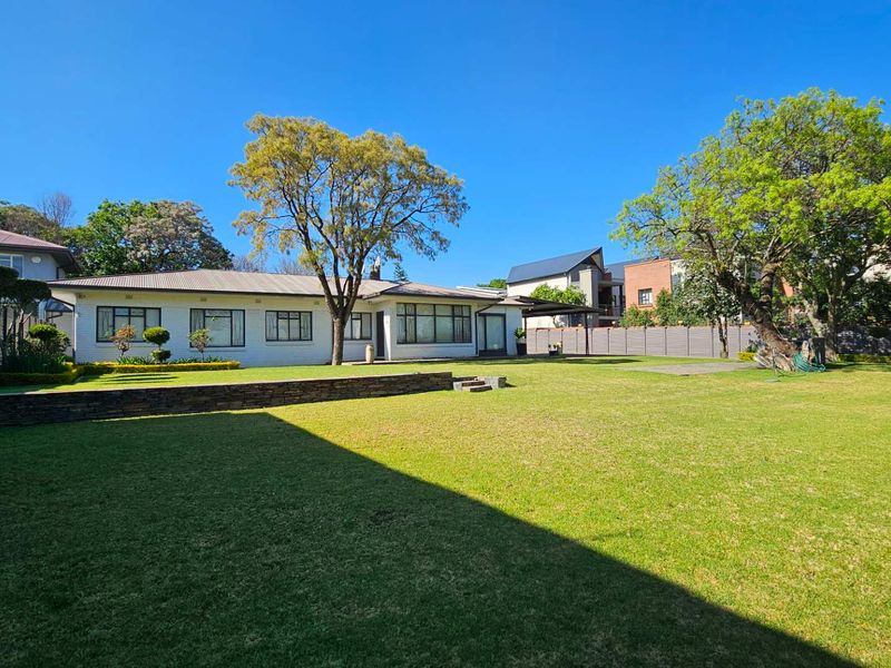 Spacious rear garden featuring a well-maintained lawn, a stone retaining wall, and a clear view of the rear building elevation.