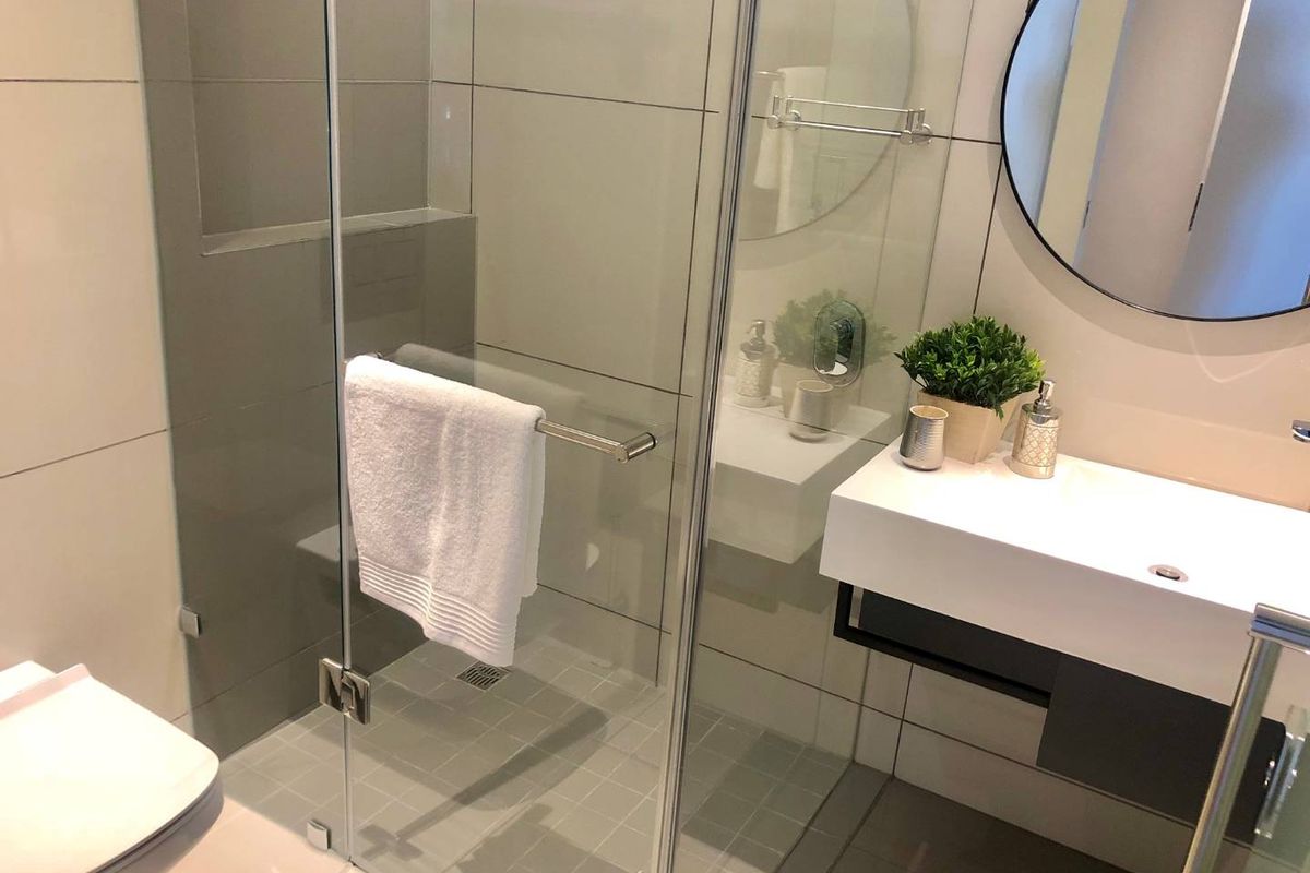 Modern bathroom featuring a glass-enclosed shower, wall-mounted vanity with basin, and contemporary neutral tiling throughout.