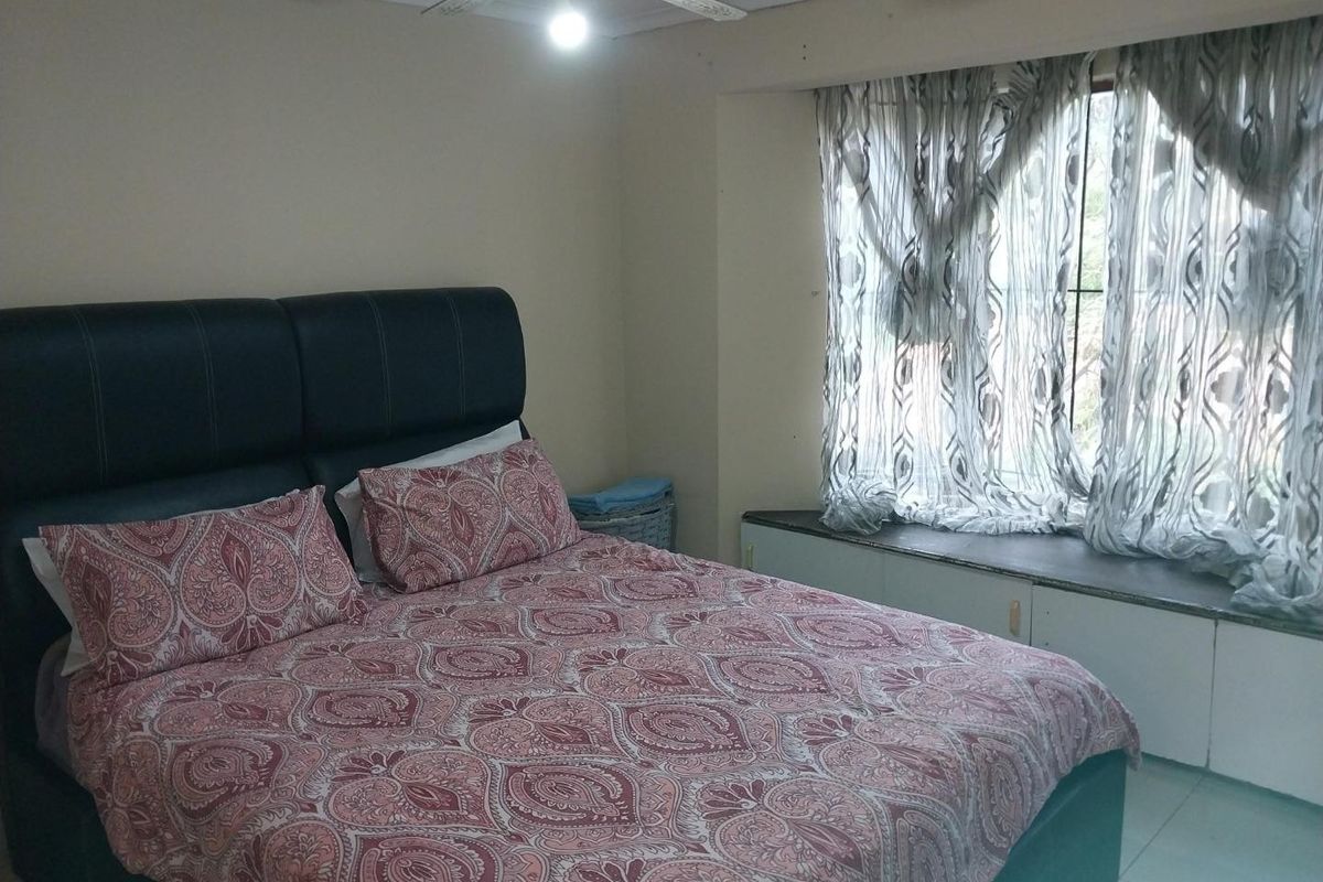 A bedroom featuring a built-in window seat, tiled flooring, and a ceiling fan, offering a functional space with potential for cosmetic updates.