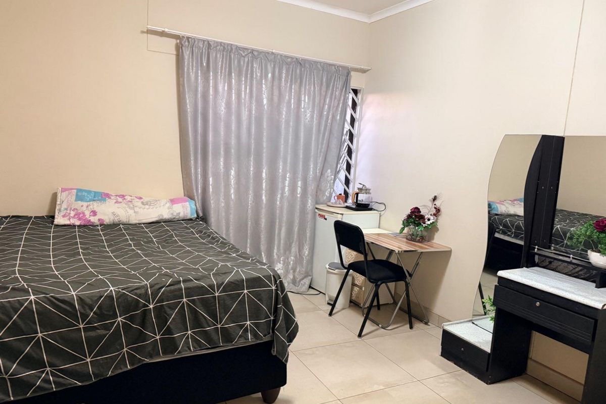 A functional bedroom featuring tiled flooring and a security gate on the window, providing a practical living space.