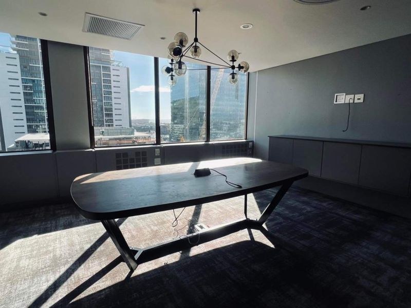 Modern office space featuring floor-to-ceiling windows with city views, built-in cabinetry, recessed lighting, and high-quality carpeting in a professional setting.