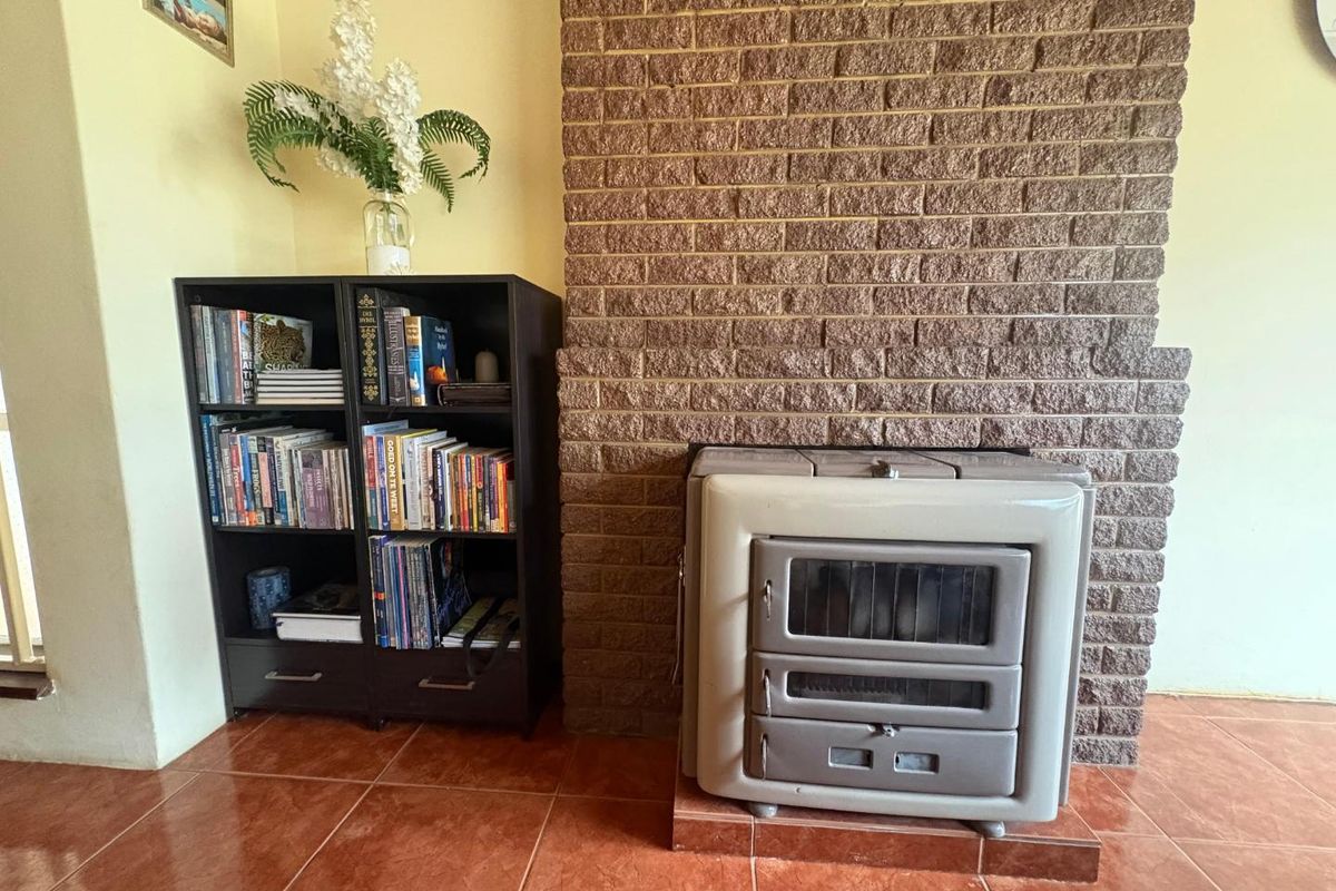 A living room area featuring a prominent exposed brick fireplace surround and a built-in wood-burning stove on tiled flooring.