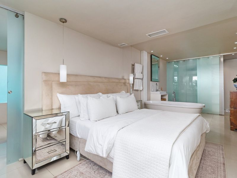 Modern bedroom suite featuring an open-plan layout with an integrated freestanding bathtub, frosted glass partitions, and high-quality tiled flooring.