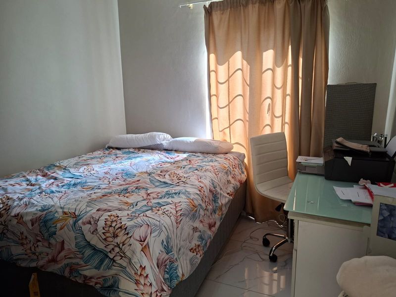 A functional bedroom featuring tiled flooring and a window with curtain rails, providing a neutral space ready for personalization.