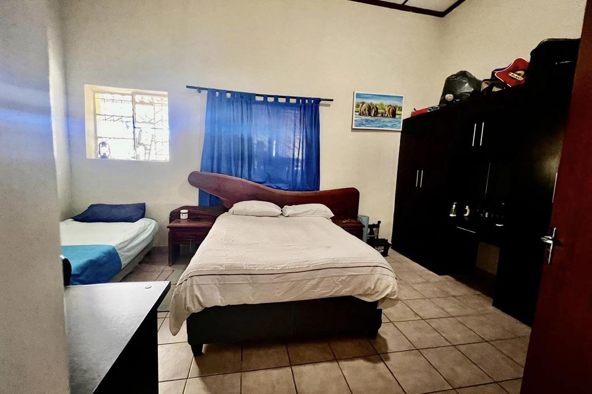 A functional bedroom featuring tiled flooring, a built-in wardrobe, and a window with natural light.