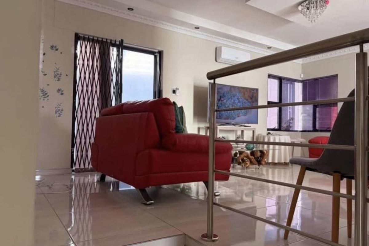 Spacious living area featuring polished porcelain tiles, modern recessed ceiling lighting, and a stainless steel balustrade overlooking the lower level.