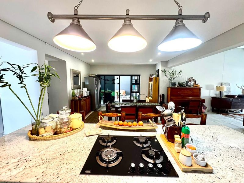 Spacious open-plan living area featuring a central kitchen island with a built-in gas hob, pendant lighting, and seamless flow to the outdoor patio.
