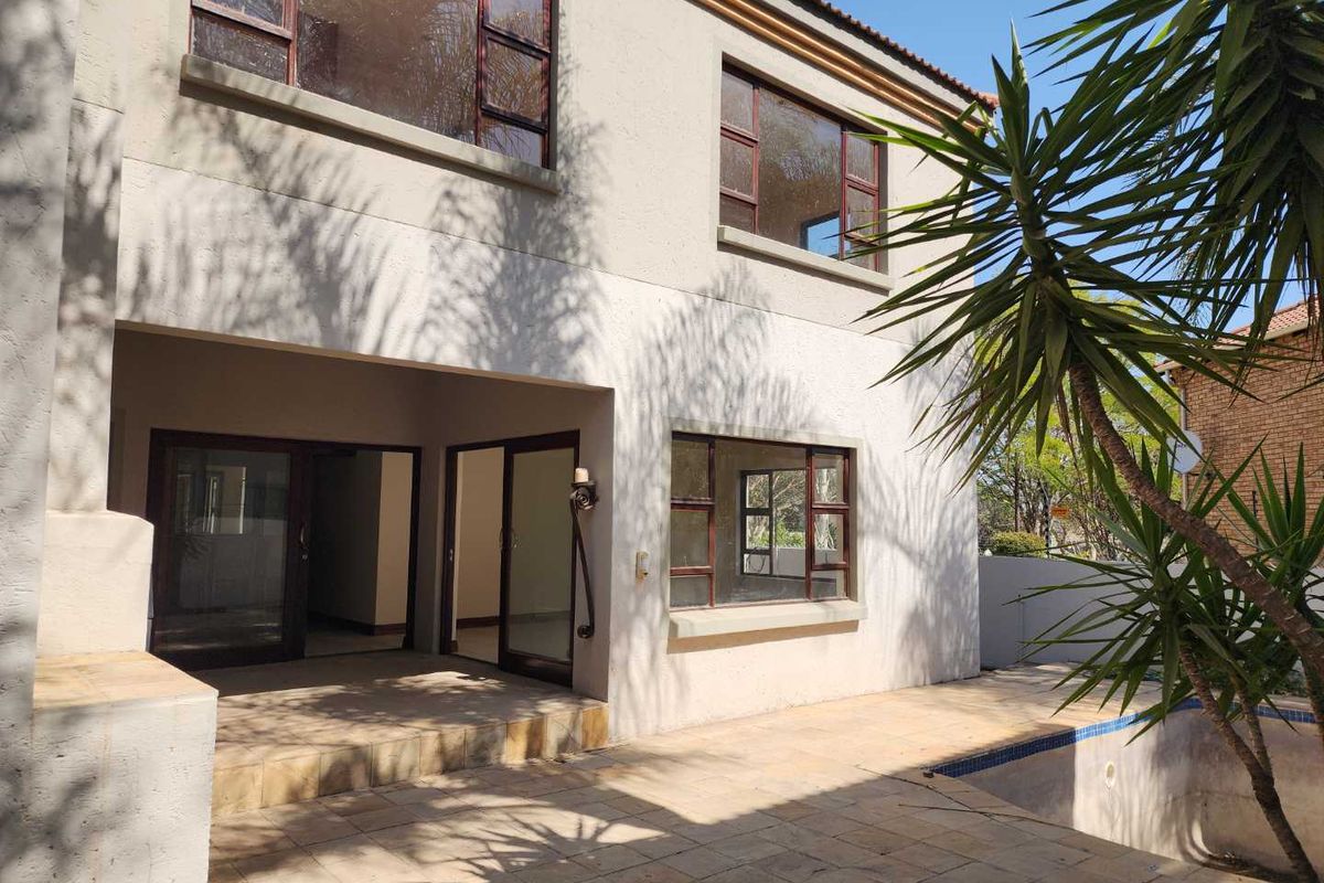 Rear view of the double-story house featuring a covered patio, tiled pool deck, and swimming pool.