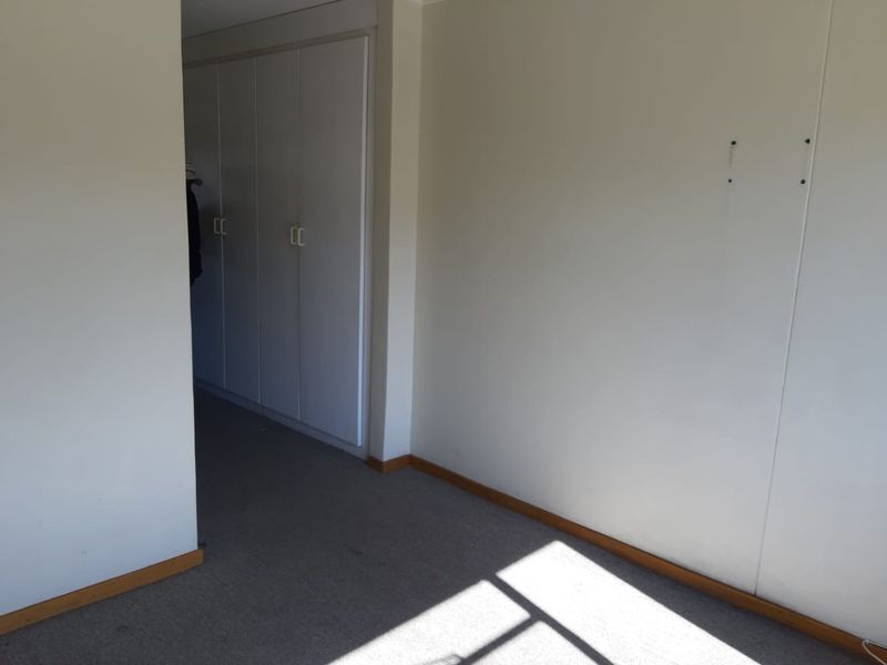 An empty bedroom featuring built-in cupboards, carpet flooring, and neutral walls, offering a blank canvas for potential interior design updates.