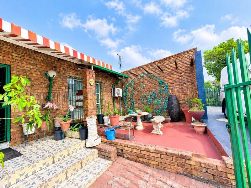 A covered brick patio area featuring a striped awning, tiled steps, and a painted concrete floor, providing a functional outdoor space.