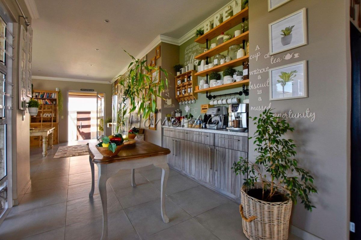 A functional kitchen area featuring modern cabinetry, open shelving, and tiled flooring, creating a warm and inviting space for food preparation and coffee service.